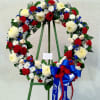 Large floral wreath with red, white, and blue flowers on a stand