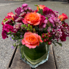 Vibrant orange roses take center stage in this mixed flower arrangement, making