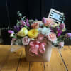Mixed pastel flower arrangement in a square box with a pink ribbon