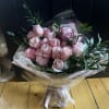 Bouquet of pale pink roses wrapped in paper with a ribbon