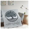 Tree-themed quilt draped over a sofa in a living room