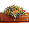 Colorful floral casket spray with mixed blooms on a wooden coffin