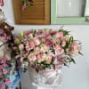 Pink floral arrangement in a white basket with a satin ribbon