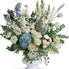 White and blue floral arrangement in a white pedestal vase