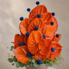 A bold cluster of glossy orange anthuriums and vivid blue spherical accents