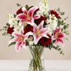 Large pink stargazer lilies unfurl above deep red roses and clusters of