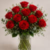 A dense cluster of red roses gathered in a clear glass vase