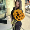 Woman holding a bouquet of bright yellow sunflowers with a ribbon wrap