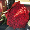 Large bouquet of red roses wrapped in red paper on a car seat