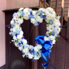 Heart-shaped floral wreath with white and blue flowers and a blue ribbon bow