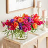 Bright mixed bouquet in a clear glass vase beside two candles
