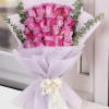 Bouquet of pink roses wrapped in pale lavender paper with a white ribbon