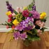 Mixed bouquet of yellow roses, purple mums, pink alstroemeria and carnations in a clear glass vase
