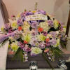 Casket spray of lavender roses, white mums, and mixed blooms with a memorial ribbon