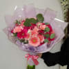 Hand-tied bouquet of pink gerbera daisies wrapped in lavender paper with a pink ribbon bow