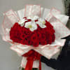 Large hand-tied bouquet of red roses with white orchids, wrapped in patterned paper and tied with a red bow.