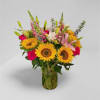 Bouquet of sunflowers, roses, lilies, and snapdragons in a glass vase