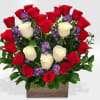 Red roses forman a heart and some white roses in a wood