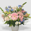 Pastel bouquet with pink gerbera, roses, and mixed blooms in a white vase