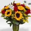 Tall vase arrangement of yellow sunflowers and red roses with yellow filler flowers and a small card
