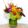 Colorful mixed flower arrangement in a green glass vase