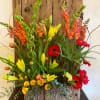 Tall rustic arrangement of yellow lilies, red gerbera daisies, and orange snapdragons in a bark-covered rectangular box