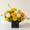 Yellow and white roses arranged in a black square vase with white filler flowers