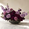 Purple and lavender roses with pink carnations in a glass bowl vase
