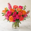Bouquet of pink and orange roses, carnations, and alstroemeria in a clear glass vase