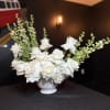 White rose arrangement in a white pedestal vase