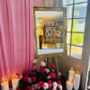 Pink and red rose arrangement with candles beside an ornate mirror sign