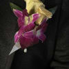 Boutonniere with cream roses and purple orchids on black fabric