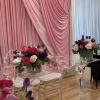 Pink and purple floral centerpieces on clear acrylic tables with draped pink fabric backdrop