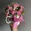 Pink rose bouquet in a white mug with a satin bow