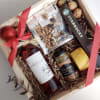A bottle of wine, cheese, pistachios, walnuts, and jam.