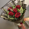 Bouquet of red roses wrapped in dark paper with baby's breath