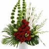 Red roses and white orchids in a white vase with tall green accents