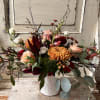 Mixed bouquet in a white ribbed vase with peach, red, and white blooms