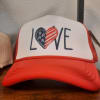 A playful red-and-white trucker hat that reads LOVE in bold navy letters