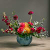 Mixed bouquet of red and pink flowers in a blue vase