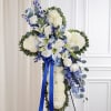 White floral standing cross with blue ribbon and accents
