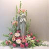 Angel statue surrounded by pink and white flowers in a floral display