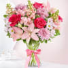 Pink and white mixed bouquet in a glass vase with a pink ribbon