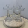 Three clear glass cross-shaped ornaments on a round white base