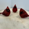 Three red decorative bird figurines on a light surface