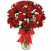 Bouquet of red roses with small white filler flowers in a glass vase
