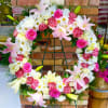 Large floral wreath with pink roses, white daisies, and lilies on an easel