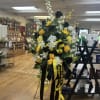 Tall black, white, and yellow funeral spray on an easel with ribbons