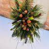 Tall tropical floral spray with orange roses and mixed greenery on a stand