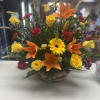 Mixed bouquet with orange lilies, yellow roses, and a yellow gerbera daisy in a basket